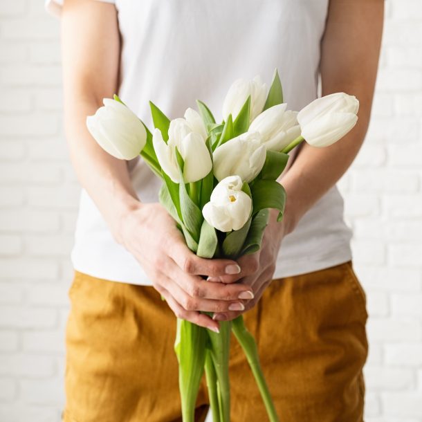 woman in yellow clothes holding bouquet of white t 8XW9UDQ